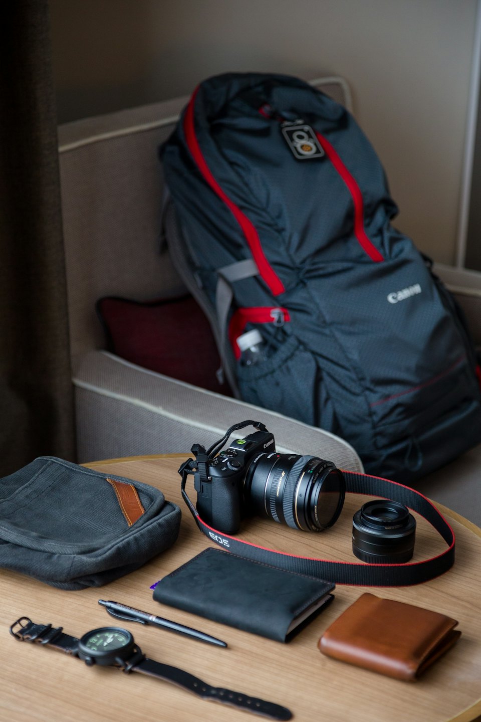 Travel essentials and photography gear arranged on a wooden table.
